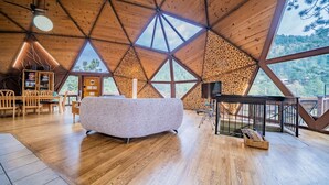 A spacious room with a high ceiling and large windows, a cozy seating area, and a wooden staircase. - The Legendary Snow Globe of Estes Park (Estes Park)