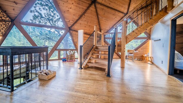 A spacious wooden interior with a high ceiling, a staircase, and a view of the outdoors. - The Legendary Snow Globe of Estes Park (Estes Park)