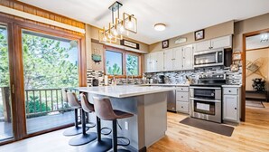 Una cocina moderna con una isla grande, taburetes de bar y vistas al exterior.