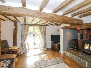 Una sala de estar acogedora con vigas de madera, una chimenea, un televisor y un espacio de descanso confortable.