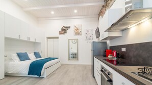 Ein modernes, kompaktes Zimmer mit einem Bett, einer Küchenzeile und einem Spiegel.