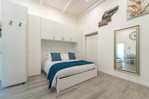 A bedroom with a bed, white wardrobe, and a large mirror. - Modern Apartment in Via Carloni by Wonderful Italy (Como)