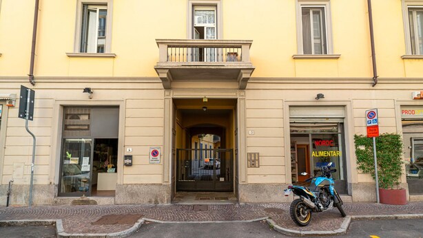 Ein gelbes Gebäude mit einem Geschäft im Erdgeschoss und einem Motorrad davor.