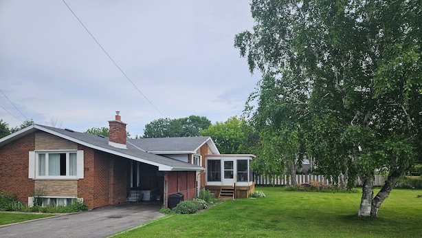 A residential property with a brick house, a covered porch, and a well-maintained lawn.