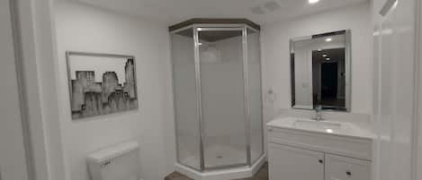Une salle de bain moderne équipée de toilettes, d’une douche à parois de verre et d’un meuble-lavabo avec un miroir.