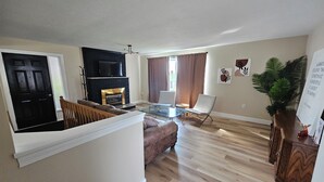 A living room with a fireplace, a television, and a dining area with a glass table.