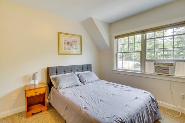 A bedroom with a bed, a nightstand, a window with blinds, and a radiator. - Beautiful Stay in Downtown Freeport, Beautiful Stay in Downtown Freeport (Freeport)
