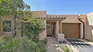 A building with a covered entrance, a garage door, and a pathway leading to the entrance. - 2 Bedroom, 2 Bathroom Luxury Townhome; 0.3 miles to Canyon Rd;  AC; Lovely Views (Santa Fe)