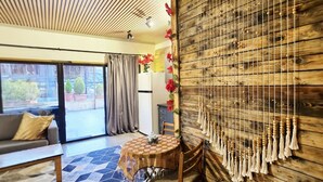 Una sala de estar moderna con techo de madera, un comedor con mesa redonda y vistas al exterior a través de amplias ventanas.