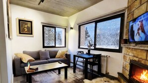 A cozy living room with a fireplace, a sofa, a coffee table, and a fur rug.