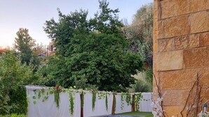 Una piscina con mosaicos azules, rodeada por un muro de piedra y una valla blanca con vegetación.