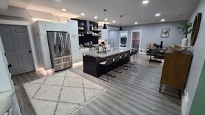 A modern kitchen with a central island, stainless steel appliances, and a dining area with bar stools.