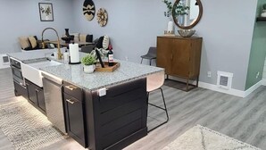 A kitchen with a granite countertop, black cabinetry, and a wooden cabinet.