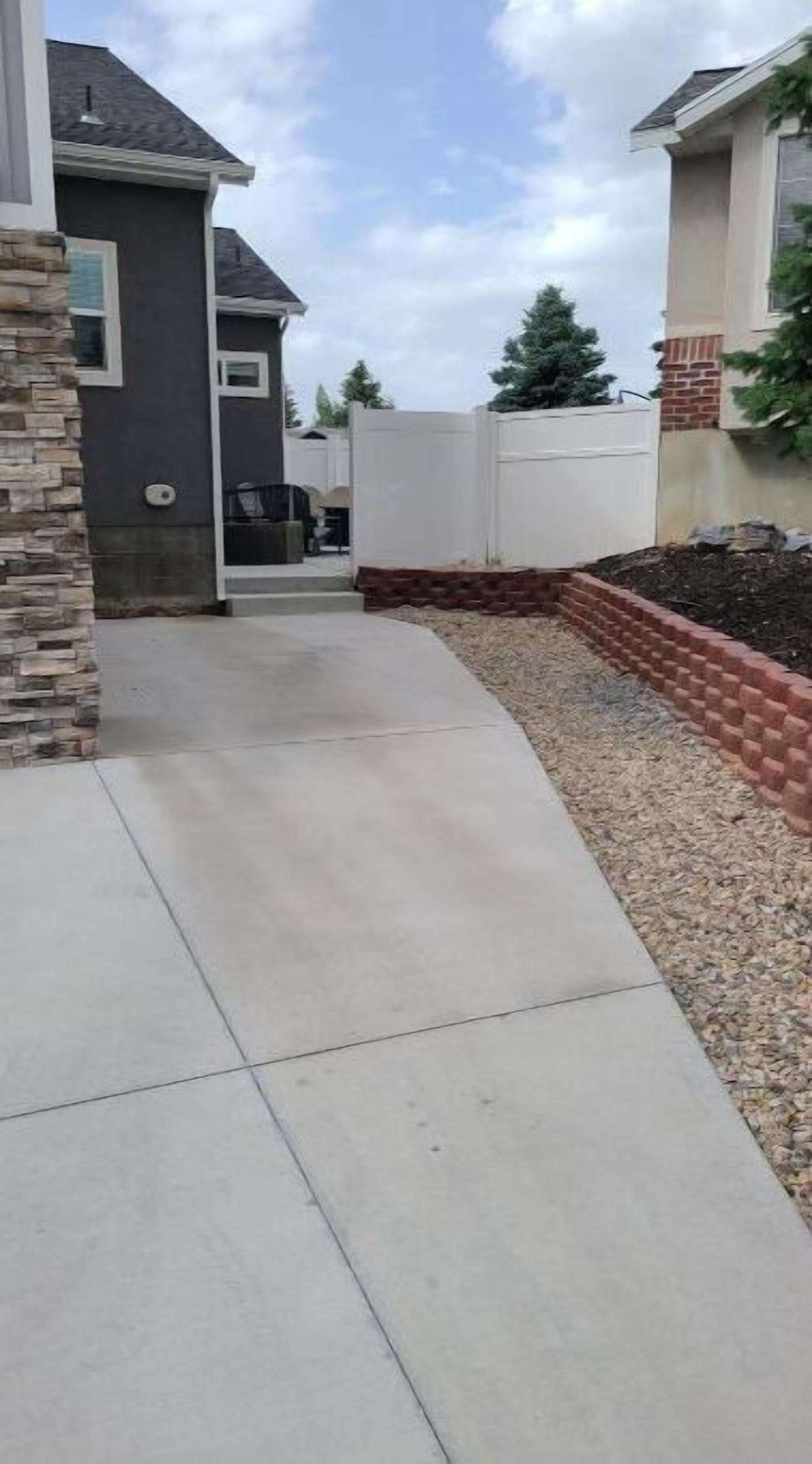 A residential driveway with a concrete path leading to a house.