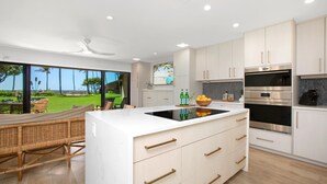 Una cocina moderna con una isla grande, electrodomésticos integrados y vistas a un jardín exuberante.