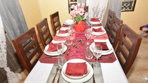 Mesa de comedor para seis personas, con servilletas rojas, platos blancos y cubiertos.