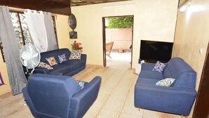 Una sala de estar con dos sofás azules, un ventilador y un televisor.