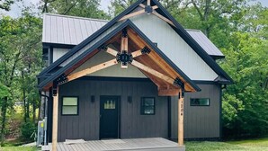A modern house with a covered porch, a garage, and a number '1204' on the side. - Kickback Cabin at Kentucky Lake (Buchanan)
