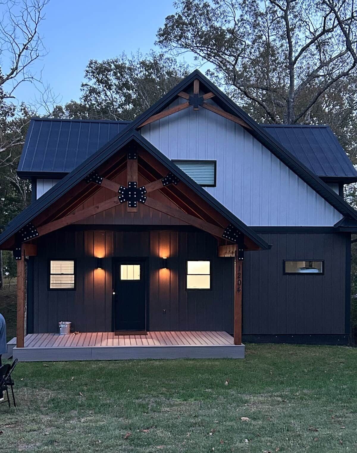 A modern house with a dark exterior, a wooden porch, and a metal roof.