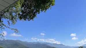 Una terraza de madera con barandilla metálica que da vistas a un paisaje montañoso.