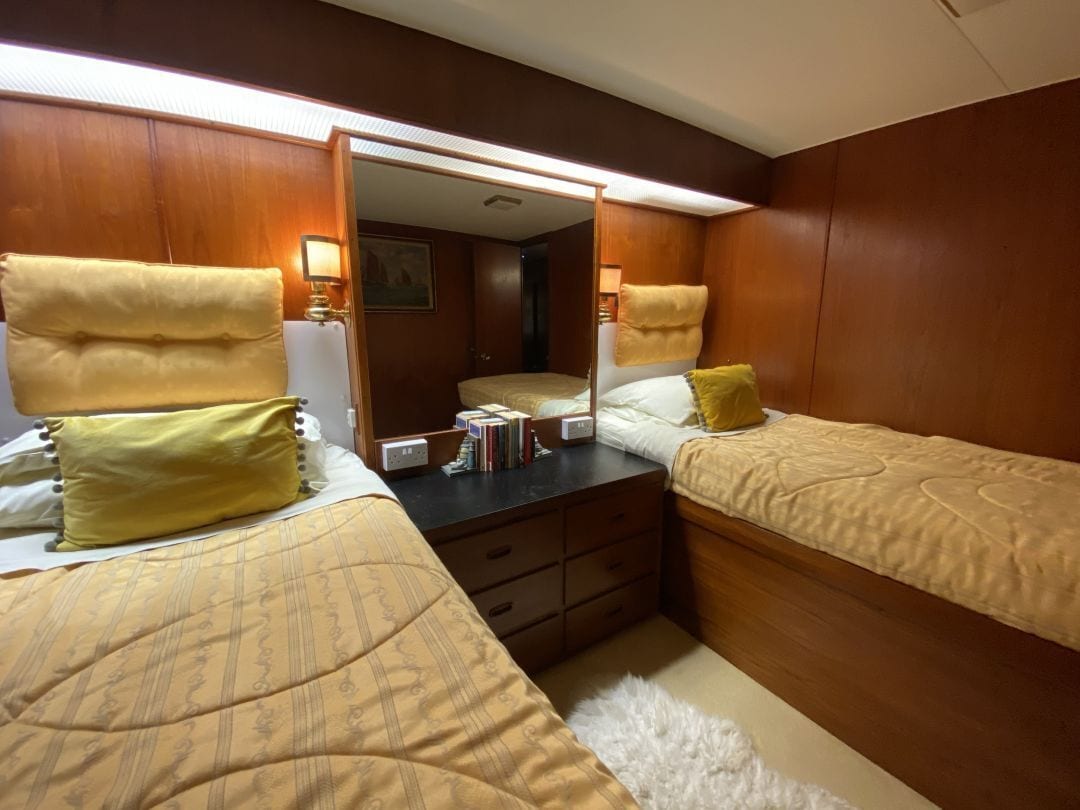 Ett hotellrum med två sängar, träpanel på väggarna, en spegel, sänglampor och ett litet bord med böcker.