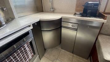 A compact kitchen with a built-in oven, a sink, and a coffee maker.