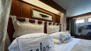 Ein ordentlich bezogenes Bett mit Kissen, auf denen "relax" steht, in einem Zimmer mit Holzvertäfelung und einem Fenster.