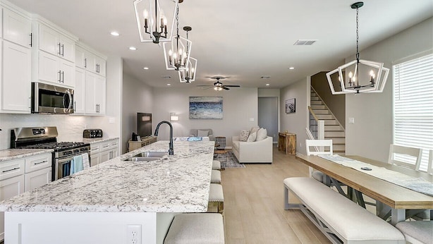 A modern kitchen with white cabinetry, a granite island, and pendant lighting.
