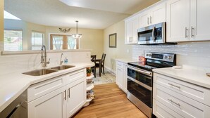 A modern kitchen with white cabinets, stainless steel appliances, and a wooden floor. - North Phoenix Home! Great Location + Private Patio (Phoenix)