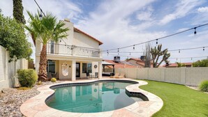 Quintal residencial com piscina, um alpendre com móveis para área externa e um espaço cercado com uma palmeira.