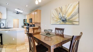 A modern kitchen with wooden cabinets, a dining area with a wooden table and chairs, and a ceiling fan. - Phoenix Home on Golf Course: Pool & Hot Tub Access (Phoenix)