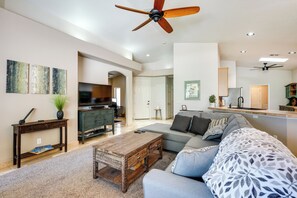 A spacious living room with a wooden coffee table, grey sofa, and a television. - Phoenix Home on Golf Course: Pool & Hot Tub Access (Phoenix)