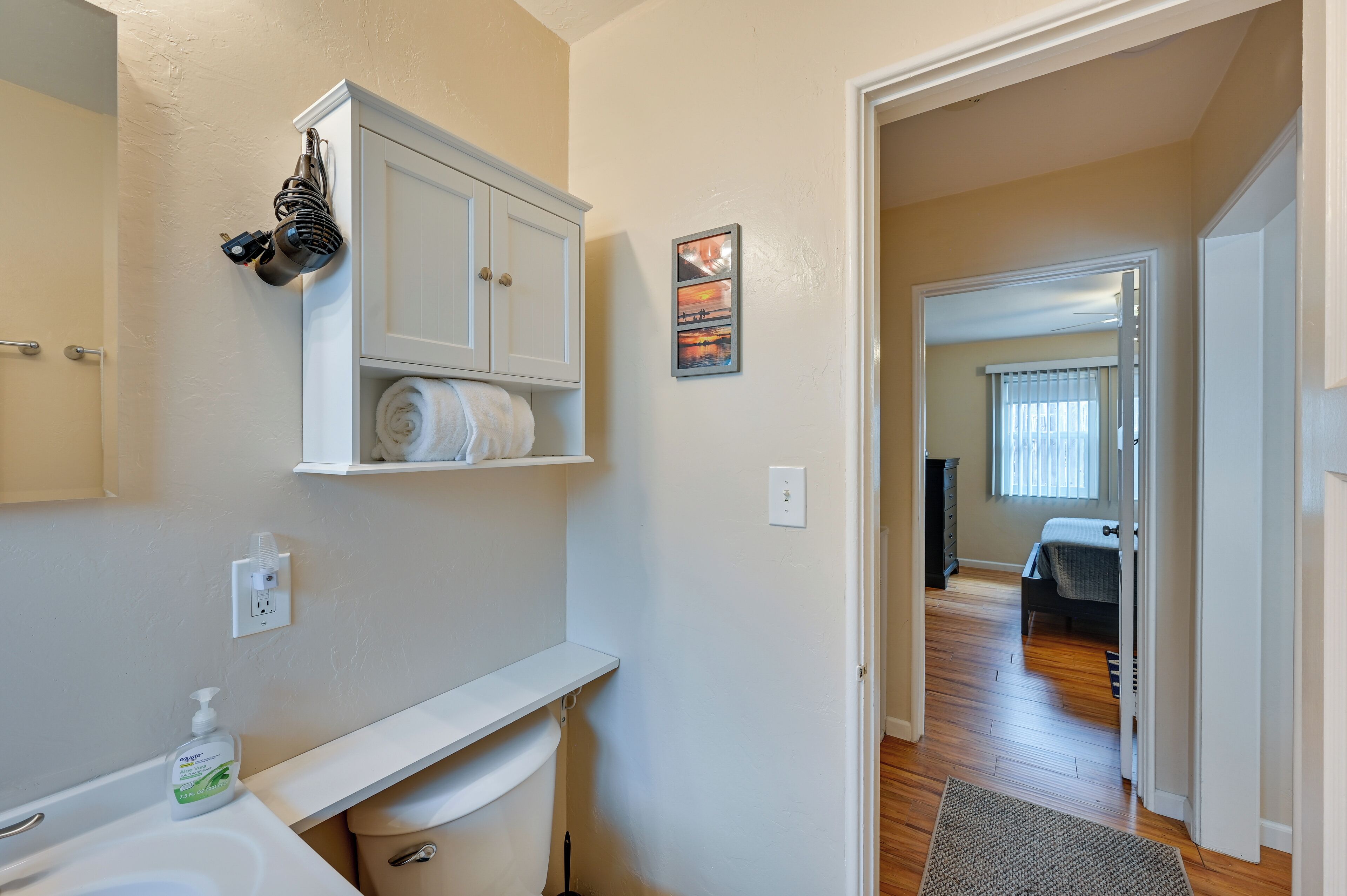A bathroom with a white sink, a toilet, a towel rack, and a shower area.