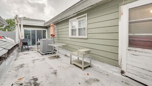 Een woning met groene gevelbekleding, een witte garageklep en een kleine tafel met een stoel.