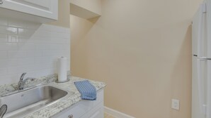 A kitchen with a stainless steel sink, a white cabinet, a countertop with a paper towel holder and a blue towel. - Refreshing Miami Apartment: 4 Mi to the Beach! (Miami)