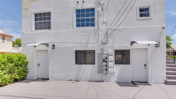 A white two-story building with two doors, a satellite dish, and a small window. - Refreshing Miami Apartment: 4 Mi to the Beach! (Miami)