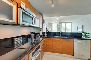 A modern kitchen with stainless steel appliances, wooden cabinets, and a black countertop.