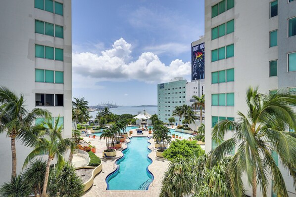 A hotel with a pool, palm trees, and a view of the ocean.