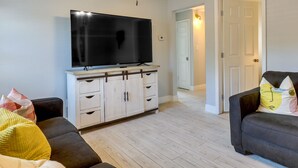 A living room with a flat-screen TV on a cabinet, a sofa, and a dark-colored couch with pillows. - Tampa Home w/ Patio - 1 Mi to Busch Gardens! (Tampa)