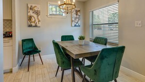A dining area with a wooden table, green upholstered chairs, a chandelier, and artwork on the walls. - Tampa Home w/ Patio - 1 Mi to Busch Gardens! (Tampa)