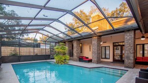 Une piscine intérieure dotée d’un toit en verre, entourée de murs en briques et d’une clôture en bois.