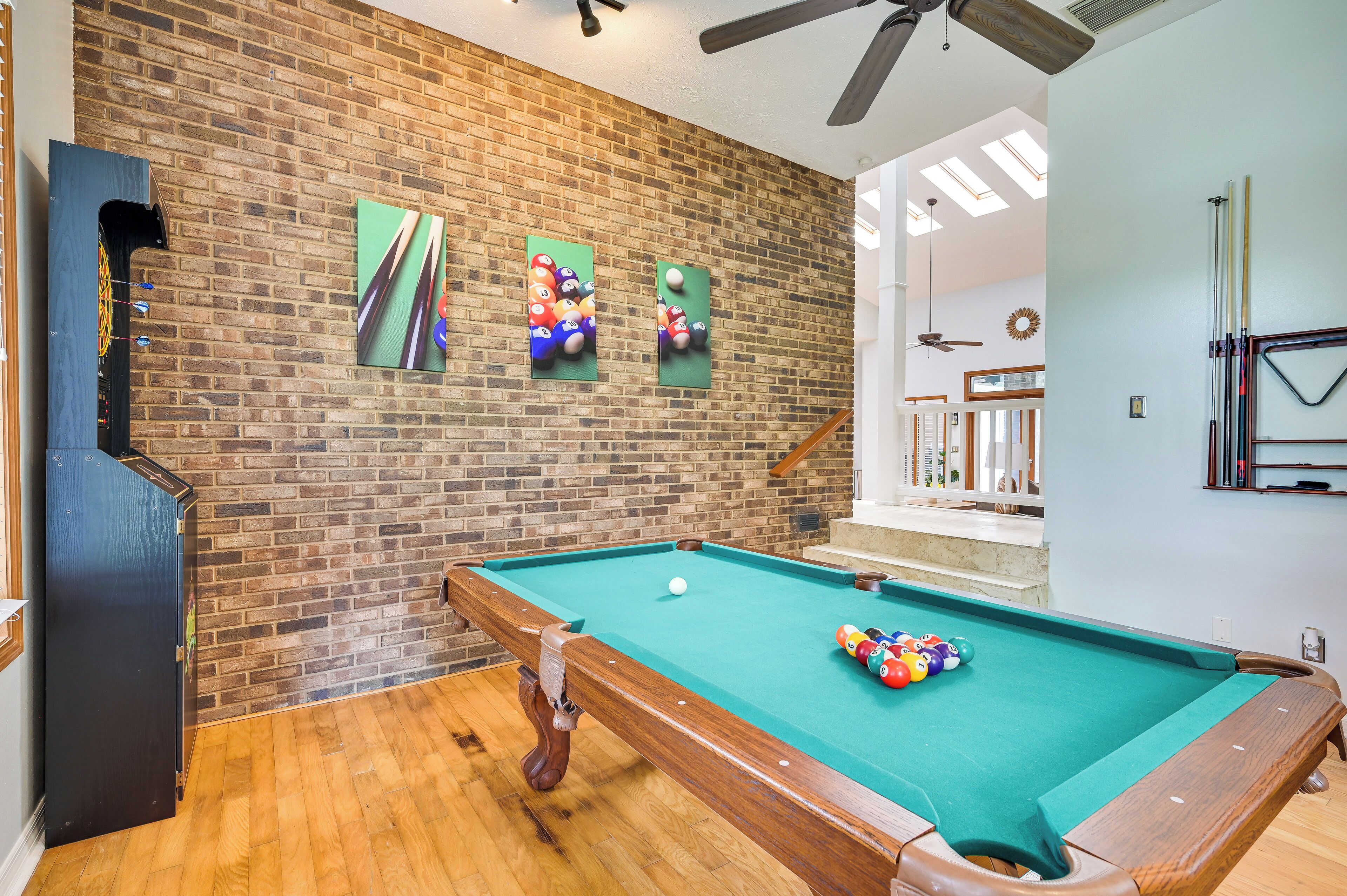 A pool table in a room with a brick wall and wooden flooring.