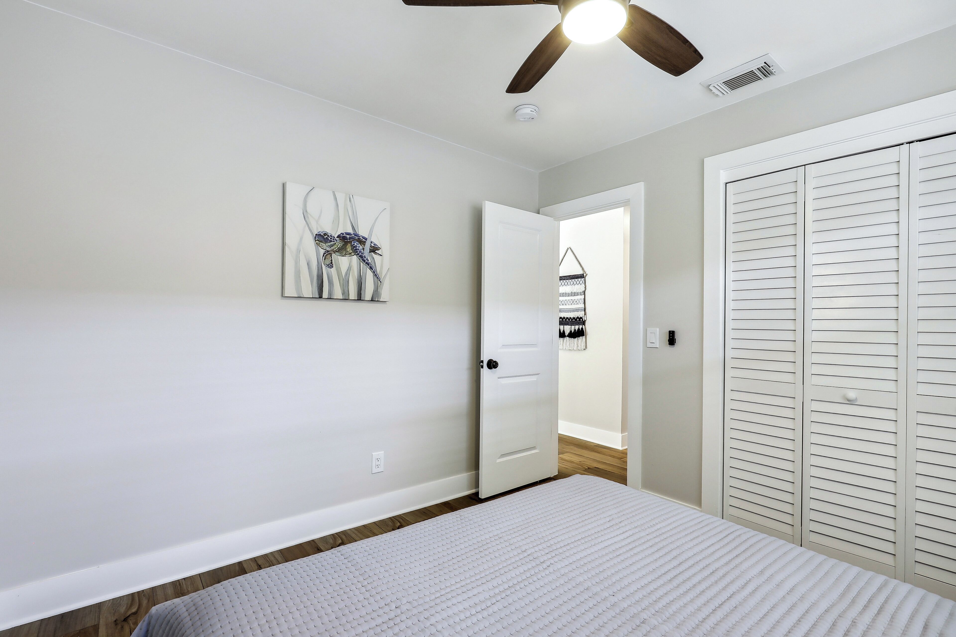 A bedroom with a bed, a ceiling fan, a door, and a closet.