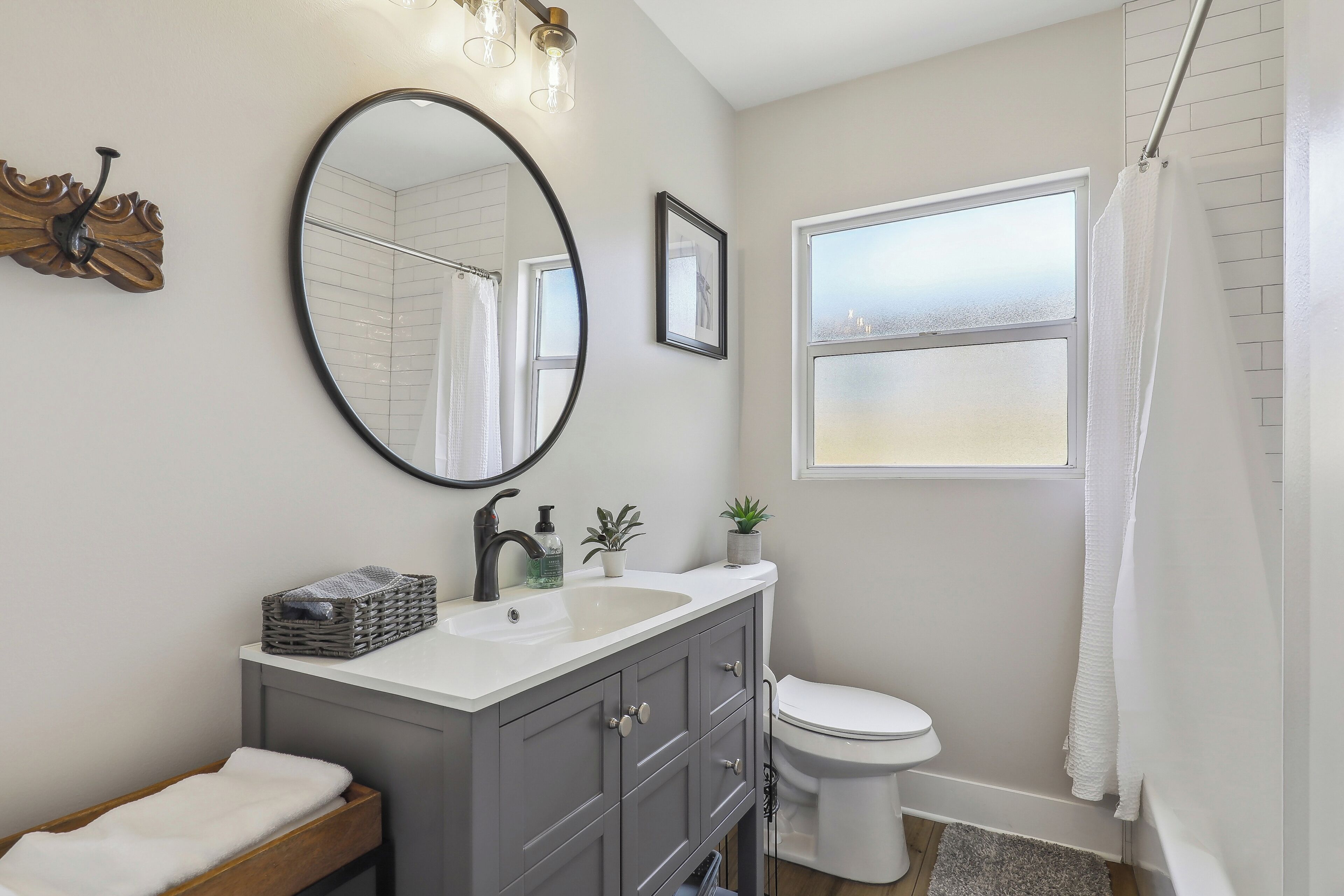 A modern bathroom with a vanity, sink, mirror, and toilet.