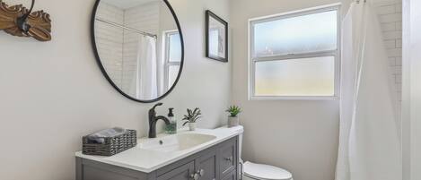 A modern bathroom with a vanity, sink, mirror, and toilet.