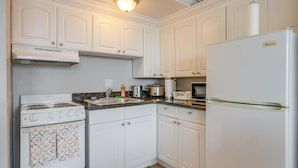 A kitchen with white cabinets, a stove, a refrigerator, and a microwave. - Downtown Jacksonville Studio w/ City Views! (Jacksonville)