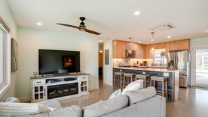 A modern living room with a large flat-screen TV, a ceiling fan, and a sofa. - Canal-front Tampa Vacation Rental w/ Private Pool! (Tampa)