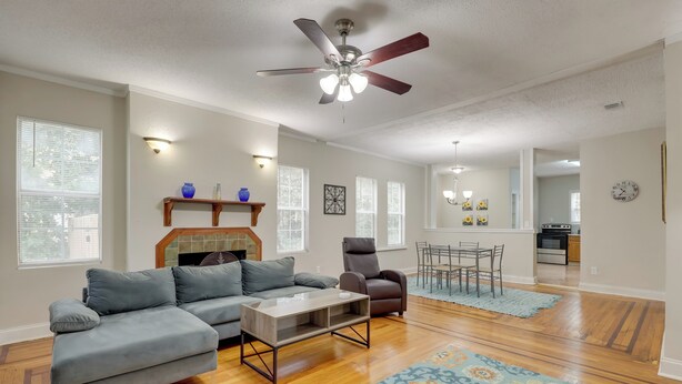 A spacious living room with hardwood flooring, a gray sectional sofa, a coffee table, a ceiling fan, and a patterned rug. - Jacksonville Vacation Rental ~ 7 Mi to Downtown! (Jacksonville)