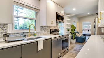 A modern kitchen with stainless steel appliances, a large window, and a view of the outdoors.