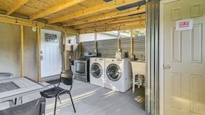 Une buanderie équipée de deux machines à laver, d’un sèche-linge et d’une table avec des chaises.